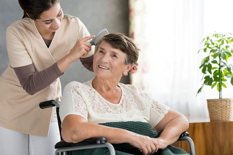 Female nurse brushing the hair of an older woman patient