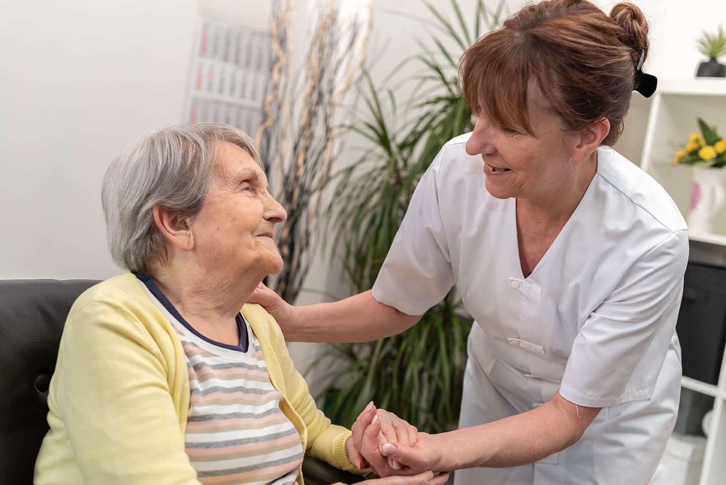 Female nurse welcoming an older woman patient