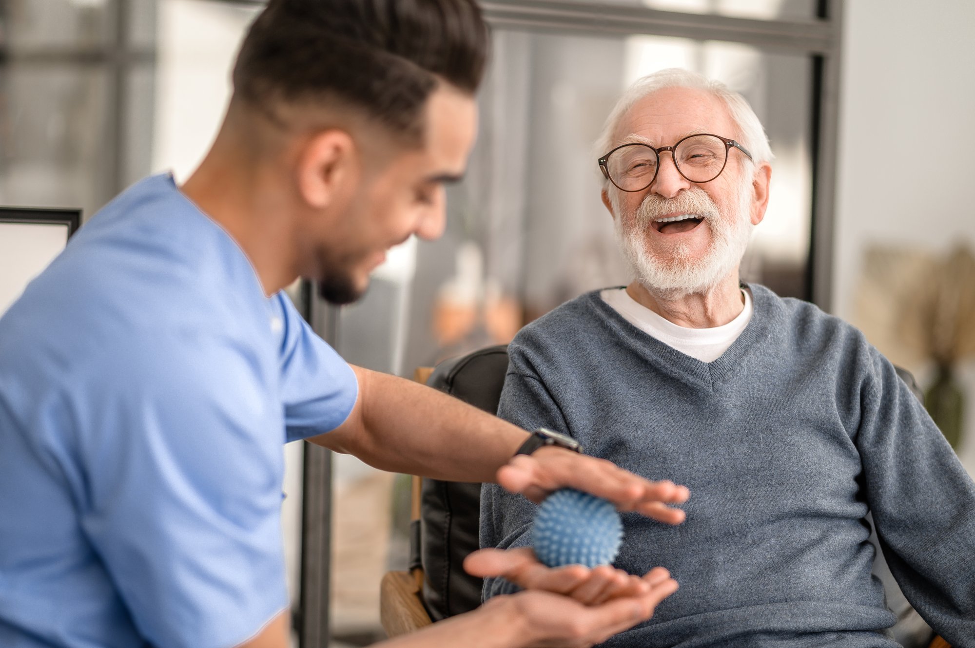 Male nurse performing physical therapy with an older male patient