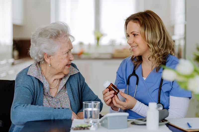 Female nurse explaining medication instructions to an older woman patient