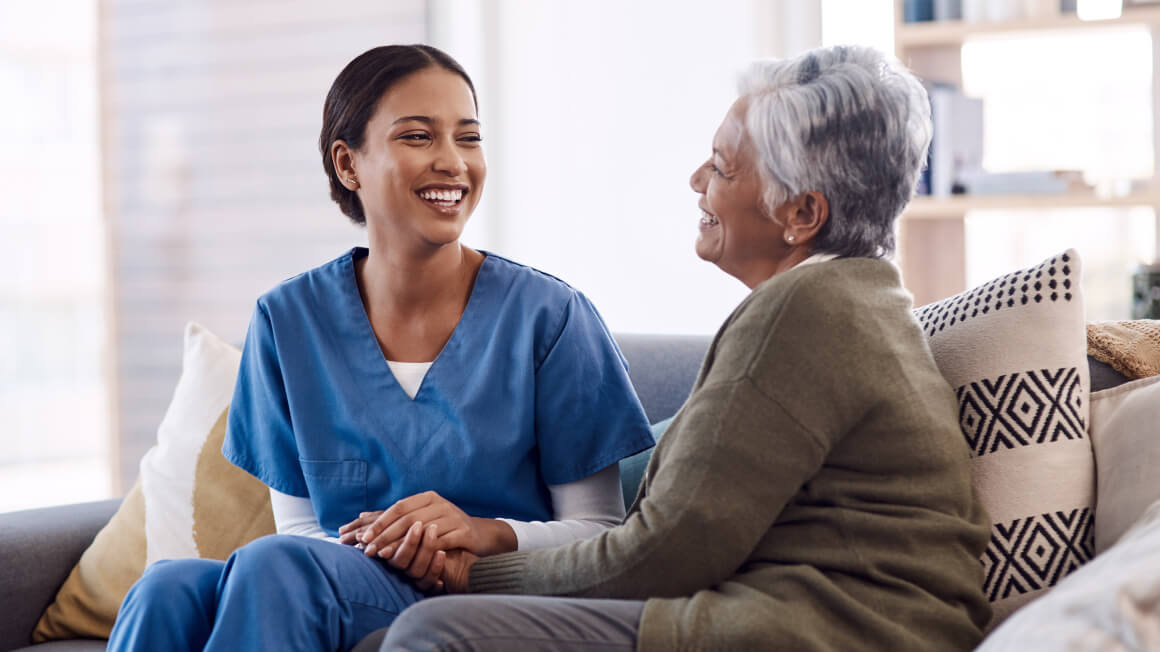 Female nurse sitting and talking with older female patient